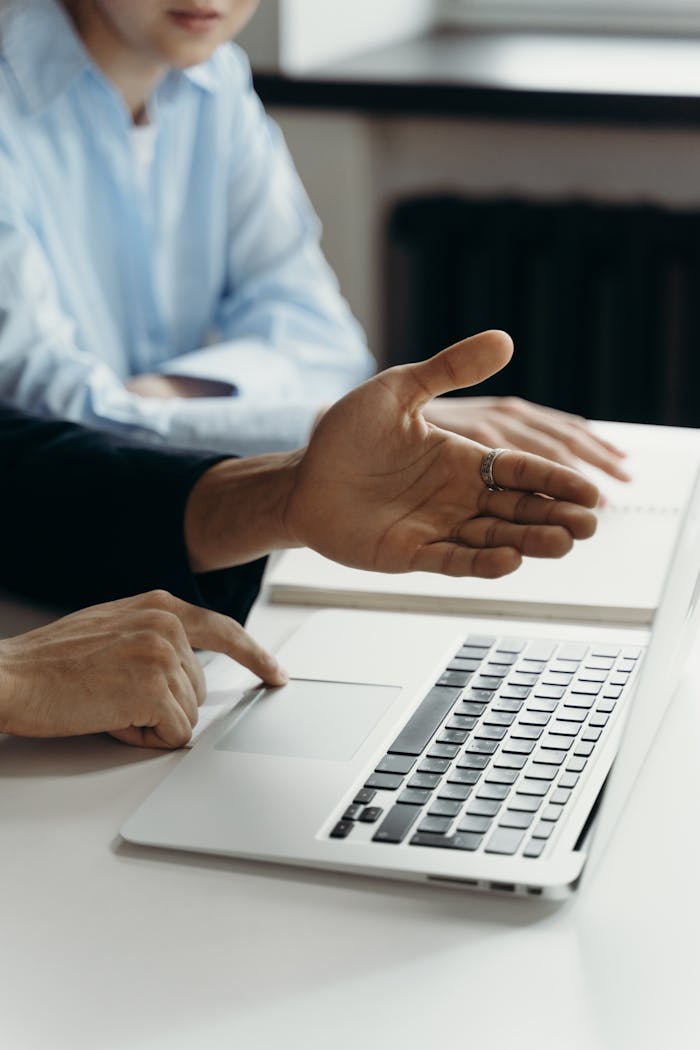 Business professionals discussing work on a laptop in an office setting.